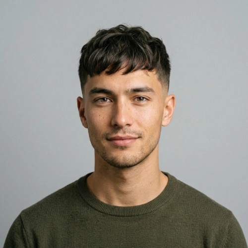 A 24-year-old male model with a relaxed Natural Edgar haircut in a studio setting.